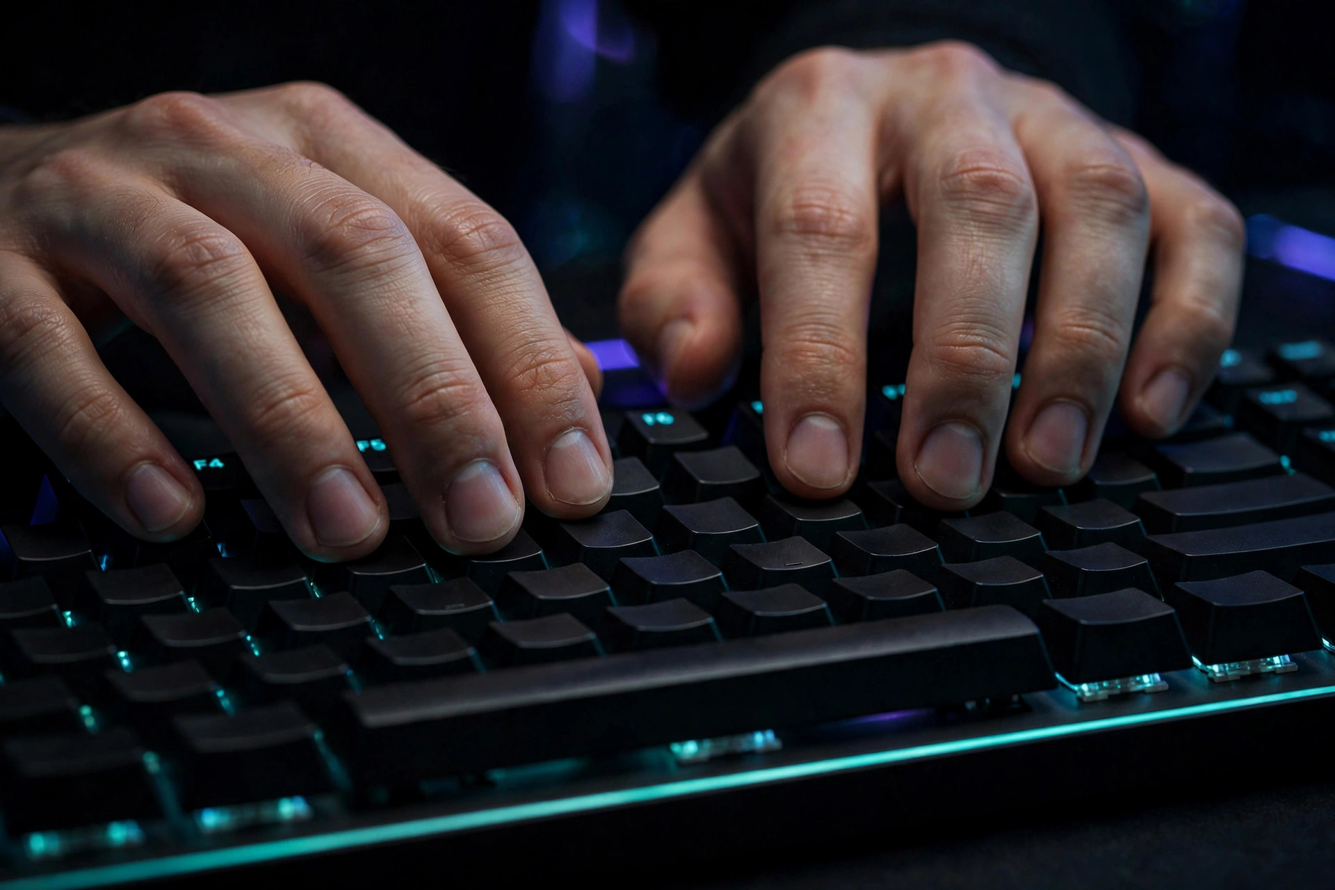 Hands in typing position on a backlit keyboard with teal underglow, fingers spread over the keys